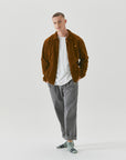 A man in a brown jacket and grey pants.