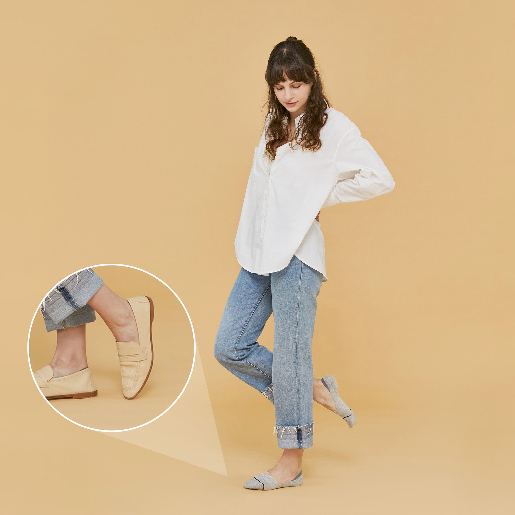 A woman standing in front of a beige background.