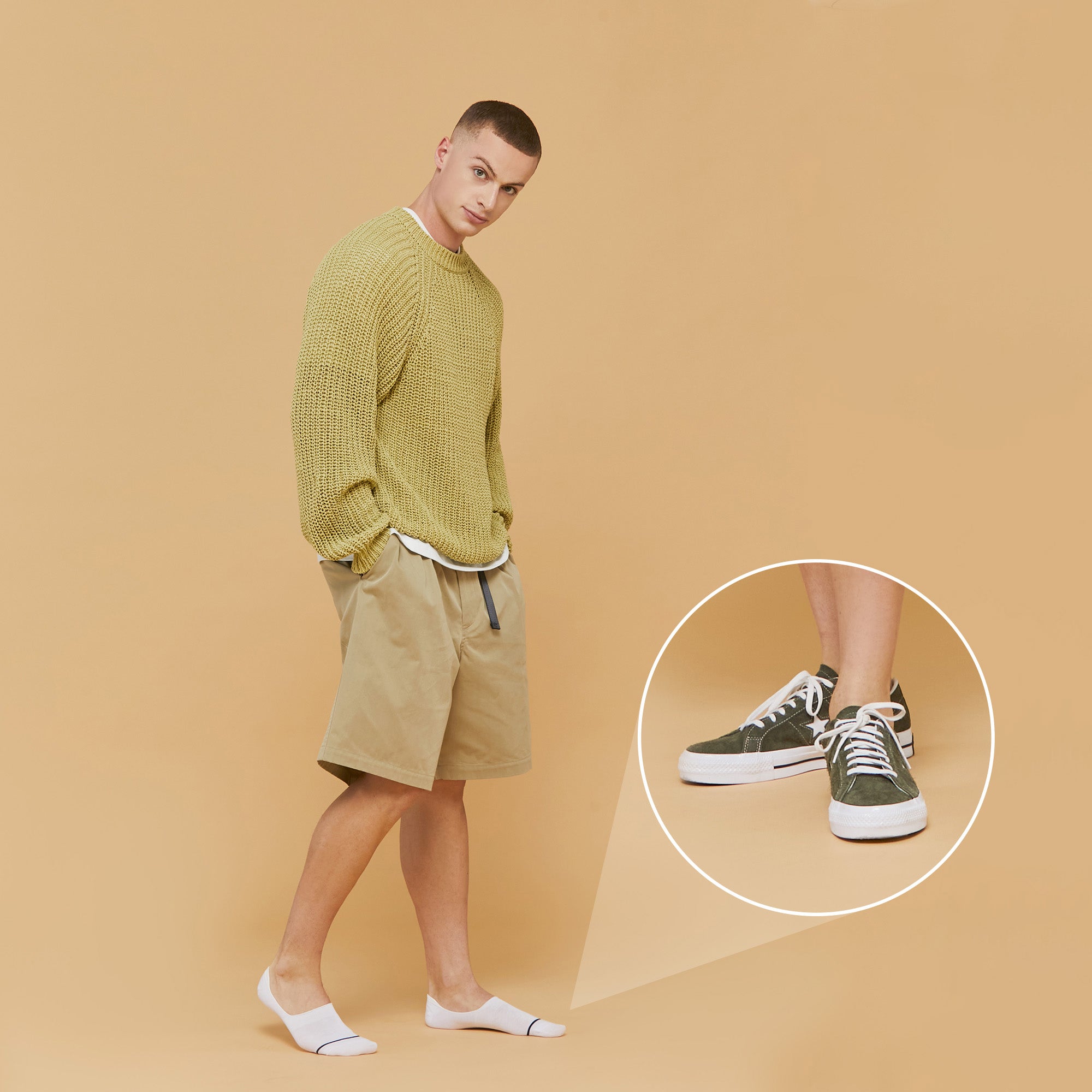 A man in a green sweater and khaki shorts.