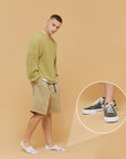 A man in a green sweater and khaki shorts.