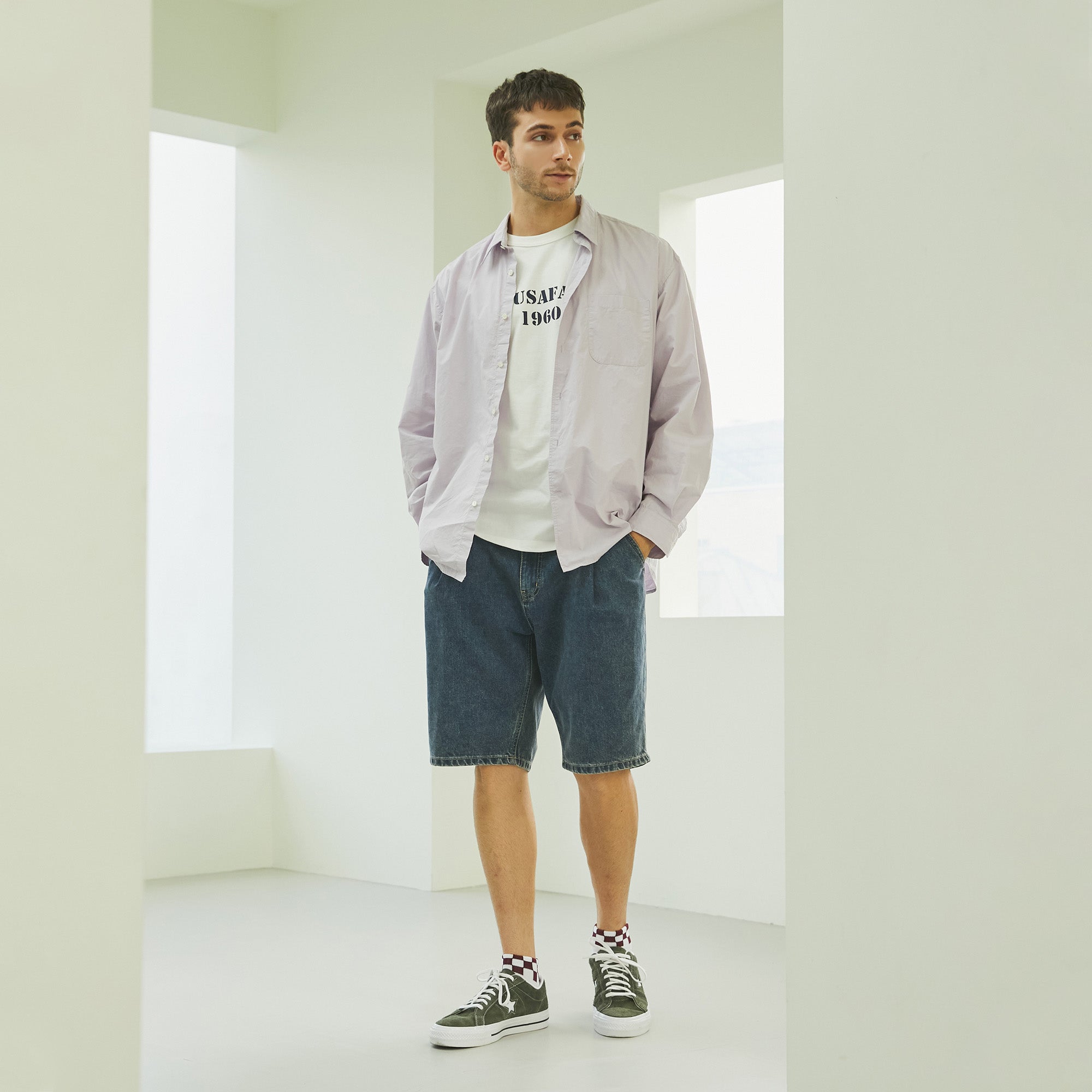 A man standing in a white room with his hands in his pockets.