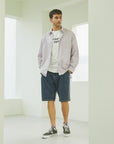 A man standing in a white room with his hands in his pockets.