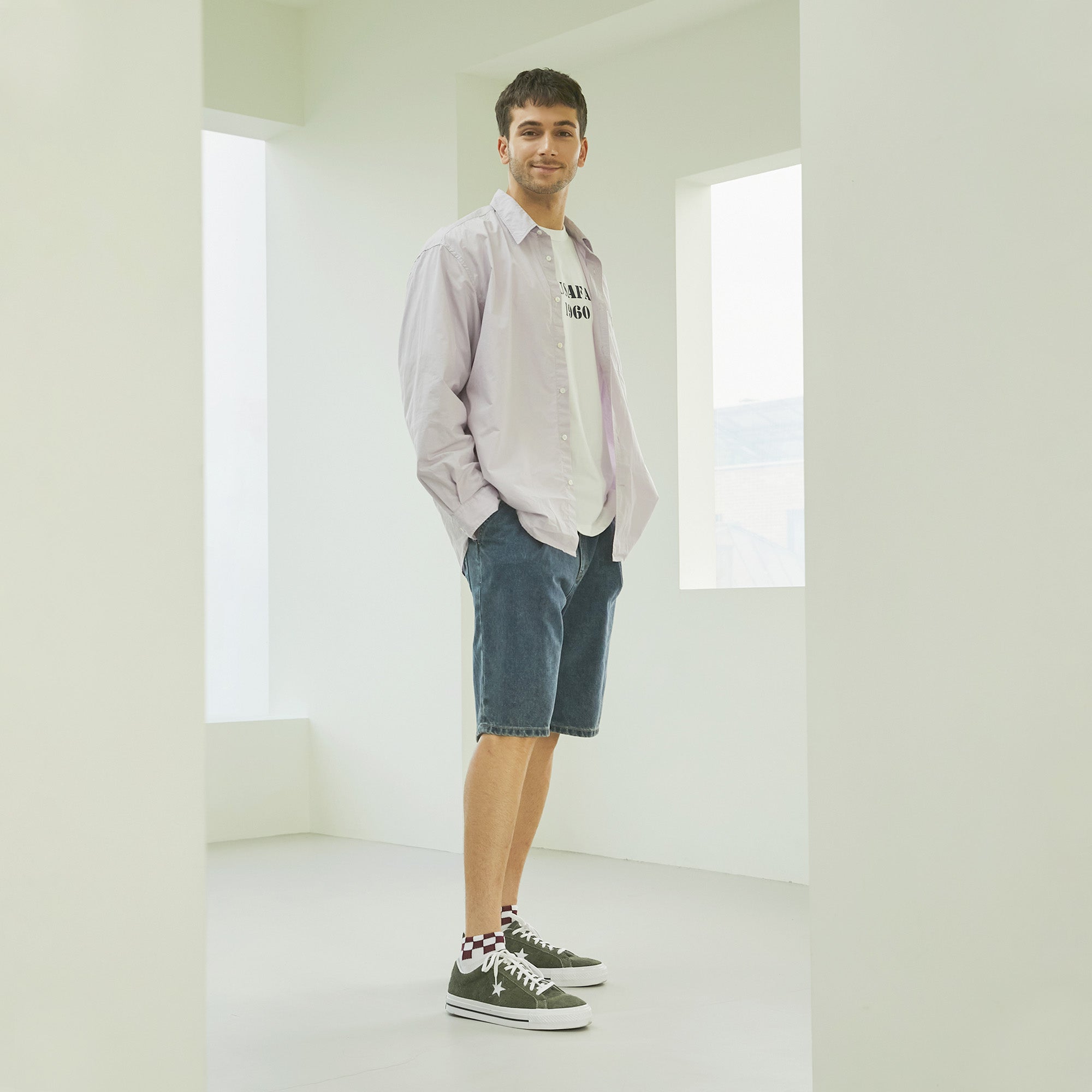 A man standing in a white room with his hands in his pockets.