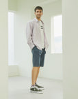 A man standing in a white room with his hands in his pockets.