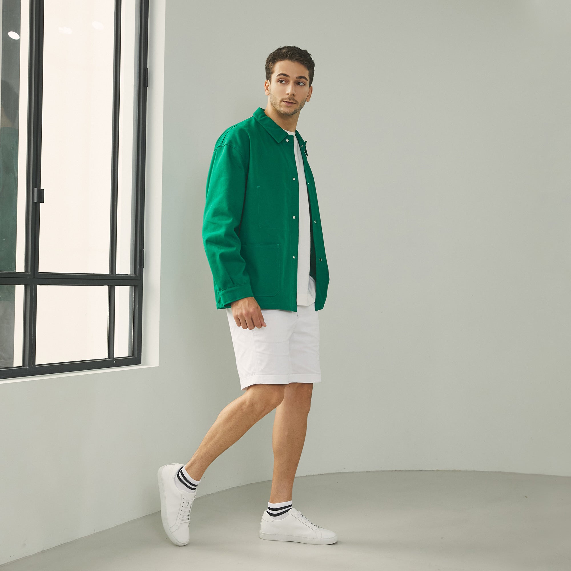 A man in a green shirt and white shorts.