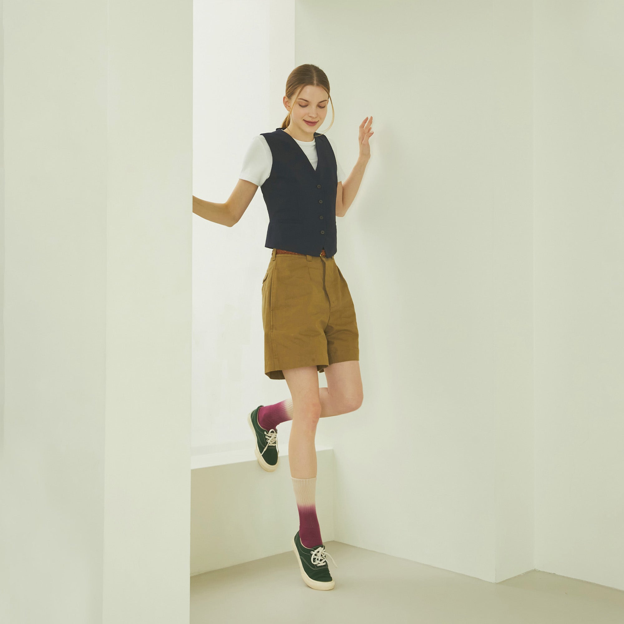 A woman standing in a room with her legs crossed.