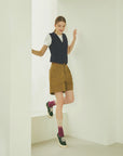 A woman standing in a room with her legs crossed.