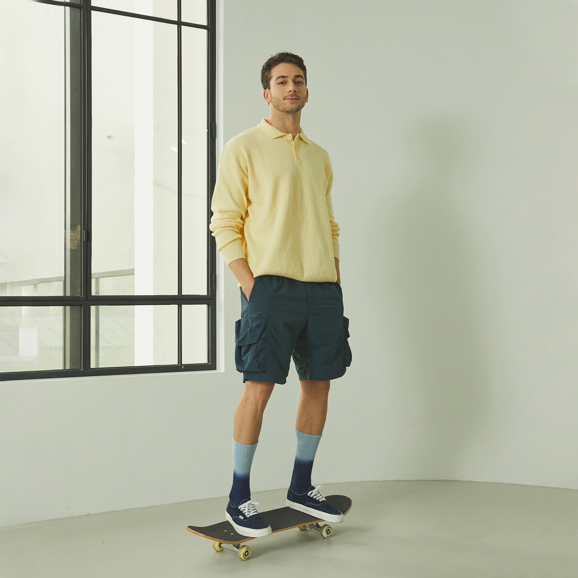 A man standing on a skateboard in front of a window.