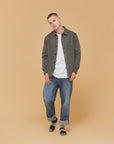 A man standing in front of a brown background.