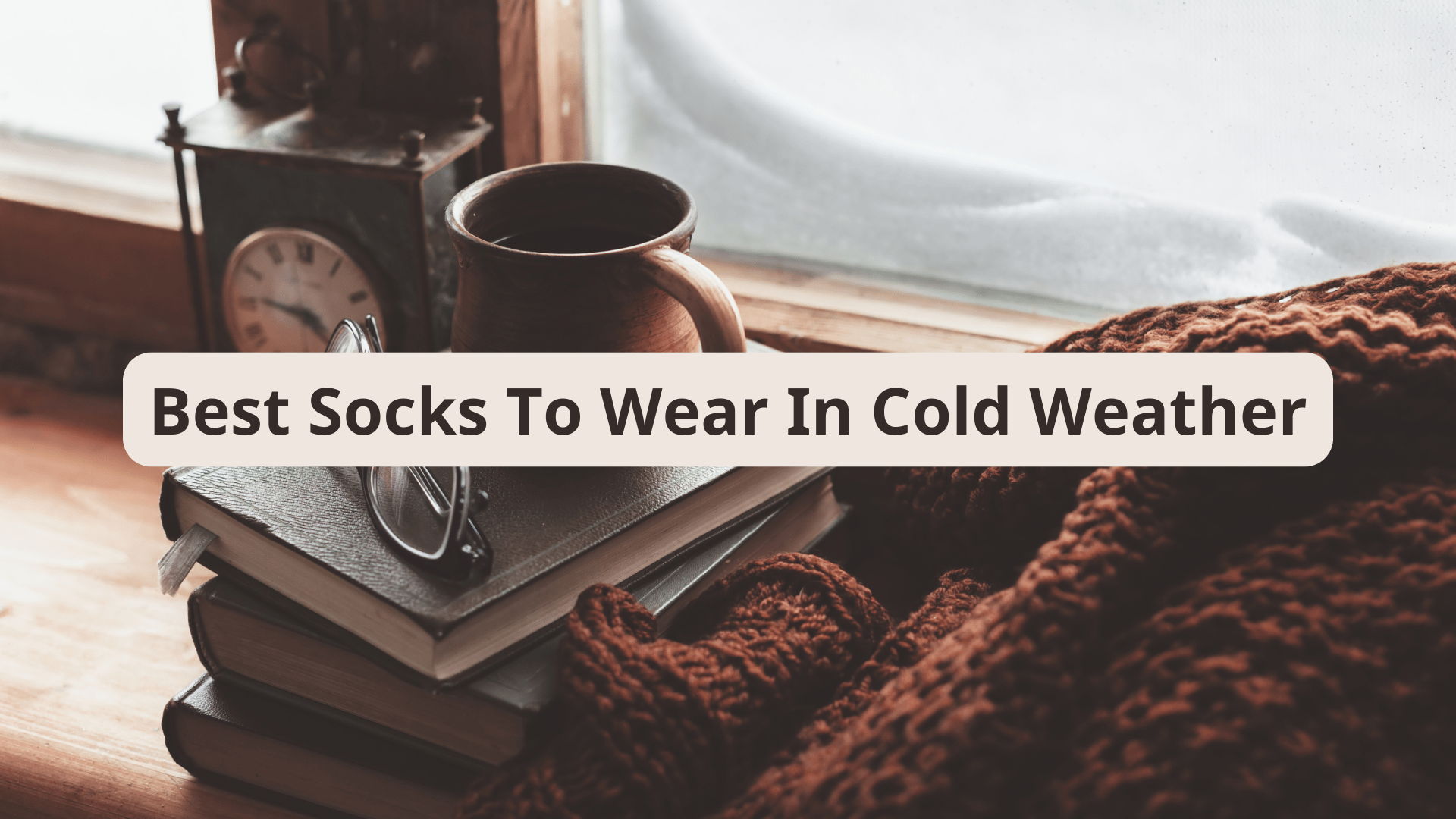 Cozy winter scene featuring a cup of coffee on top of stacked books, with a blanket and a frosted window in the background, and text that reads "Best Socks To Wear In Cold Weather" in a beige text box.